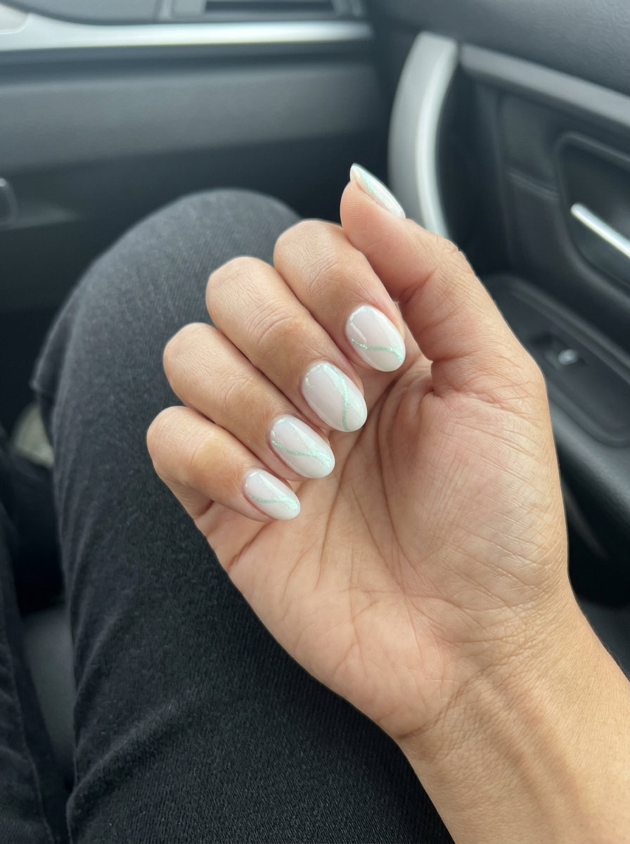 Milky white nails with mint green shimmer lines for daily wear. Ethereal green summer nails 2026.
