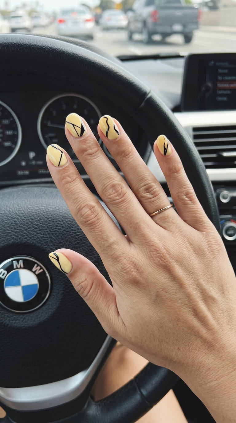 Short Round Summer Nails 2026: Butter Yellow Art Short round summer nails 2026: Artistic butter yellow with matte black abstract lines for fashion-forward looks.