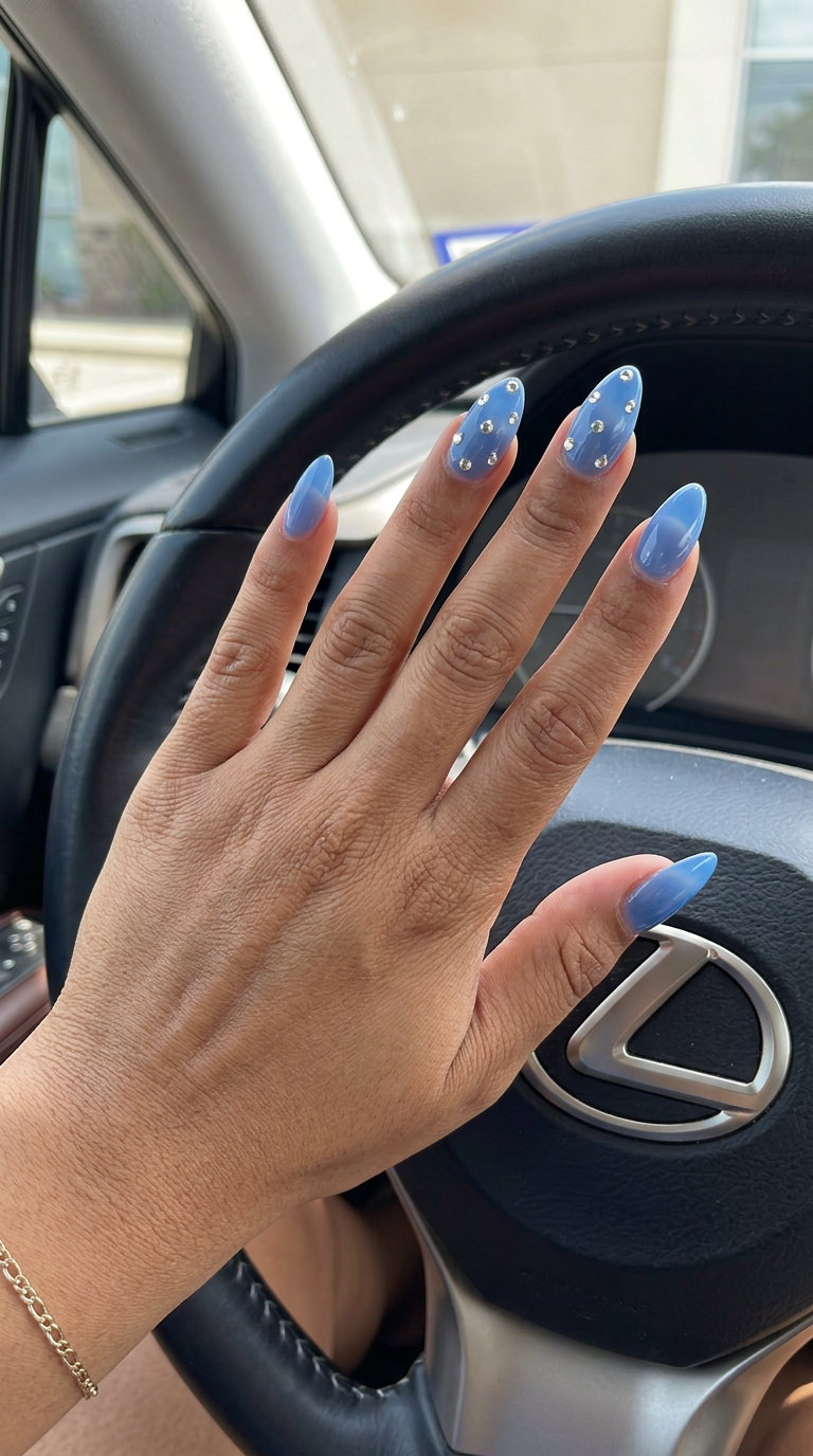 Sheer blue nails with rhinestone accents for trending summer nails 2026. Glamorous party outfit.