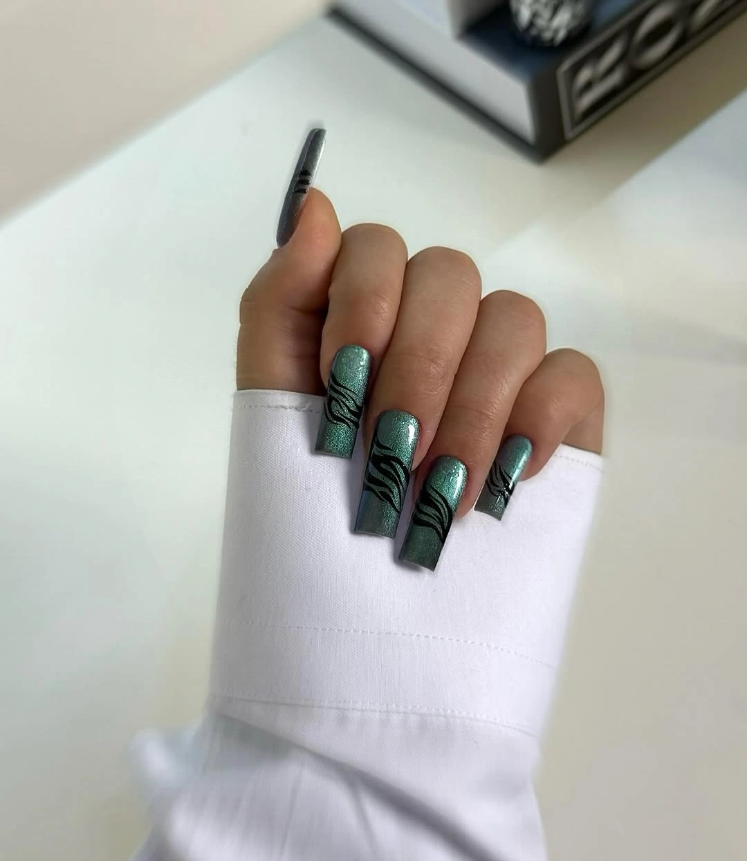august nails color 2026 Metallic Sage Green Nails with Graphic Black Details