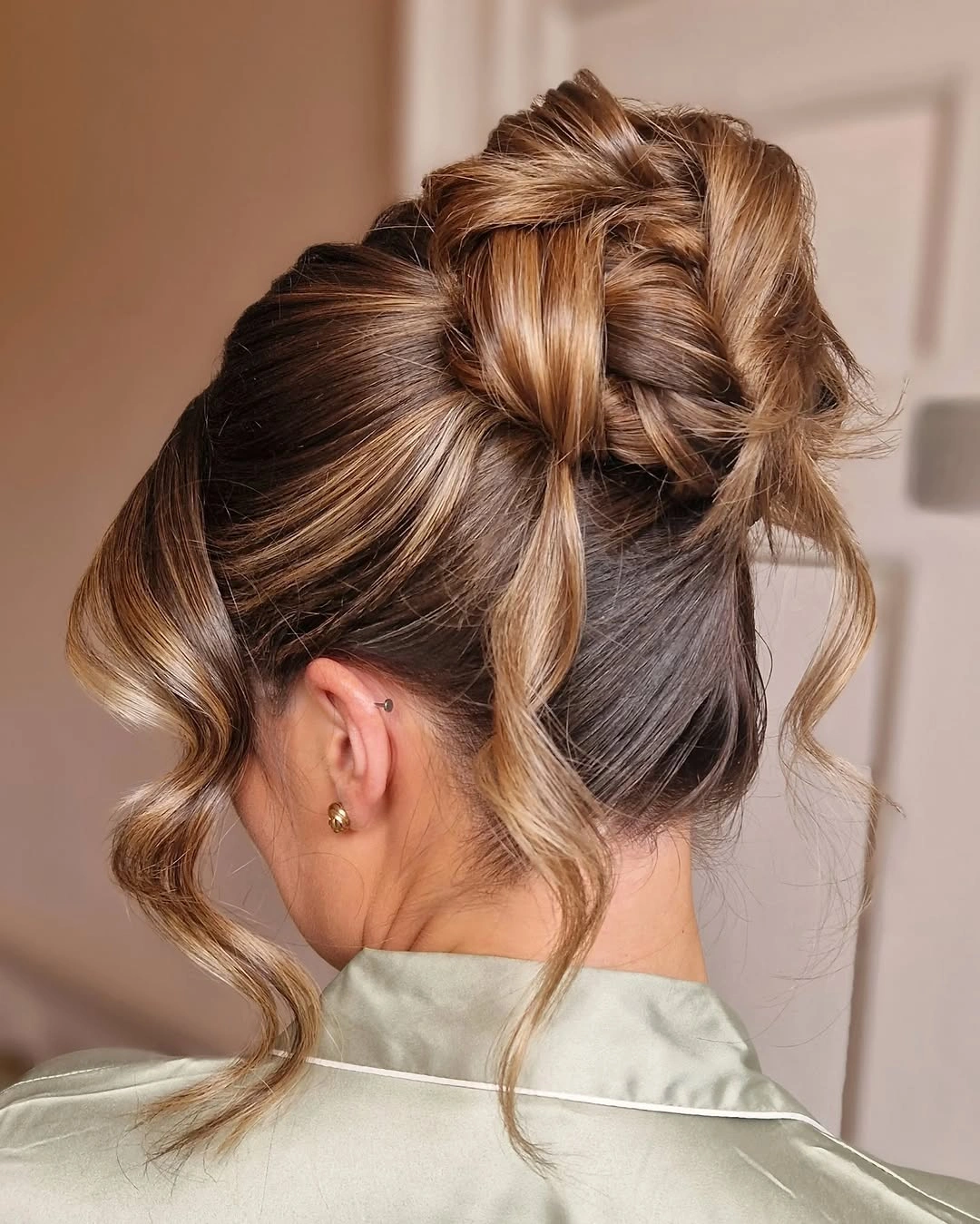 bridesmaid hairstyling A Modern High Bun with Face-Framing Waves