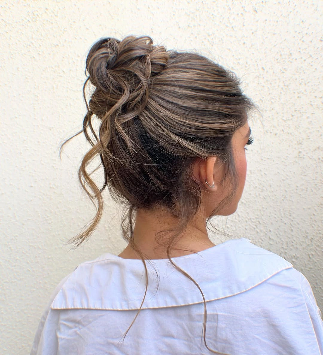 Fall hairstyles for wedding guests 2026 Relaxed Textured Bun with Soft Highlighted Dimension