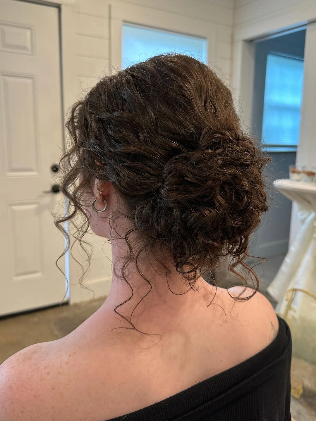 Fall hairstyles for wedding guests 2026 Romantic Curly Low Bun with Soft Autumn Texture