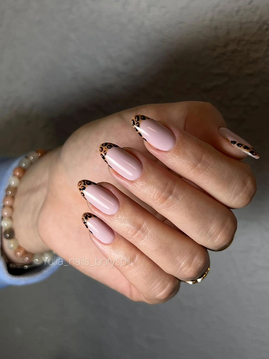 short nude nails with leopard french tips and pearl bracelet