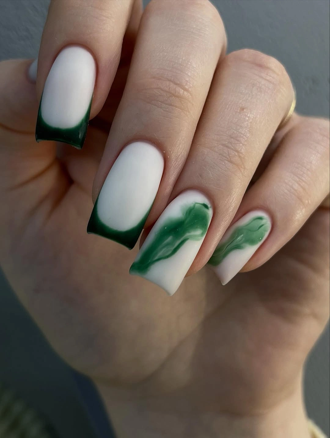 white square nails with green french tips and marble accents