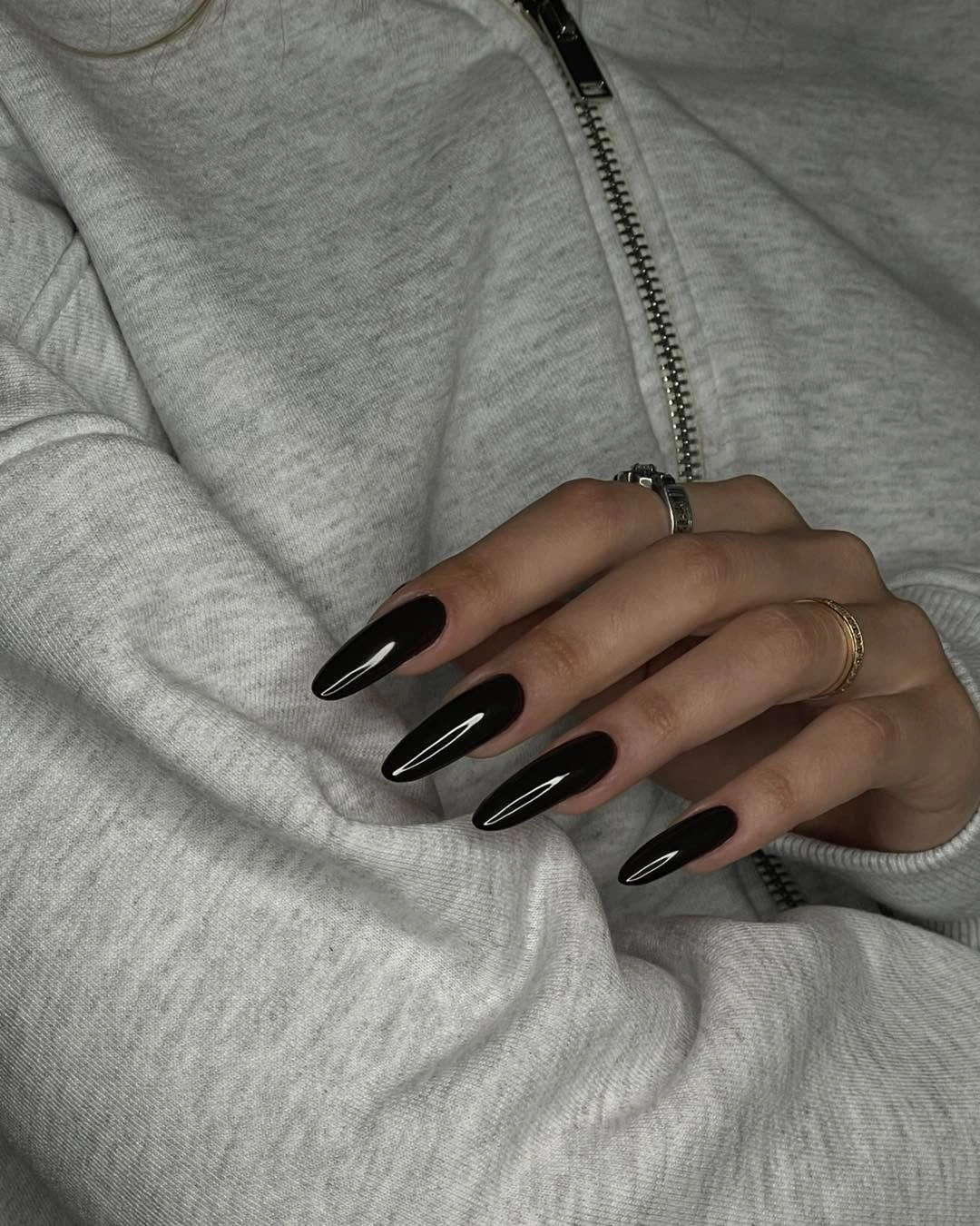 long glossy black almond nails styled with a gray hoodie