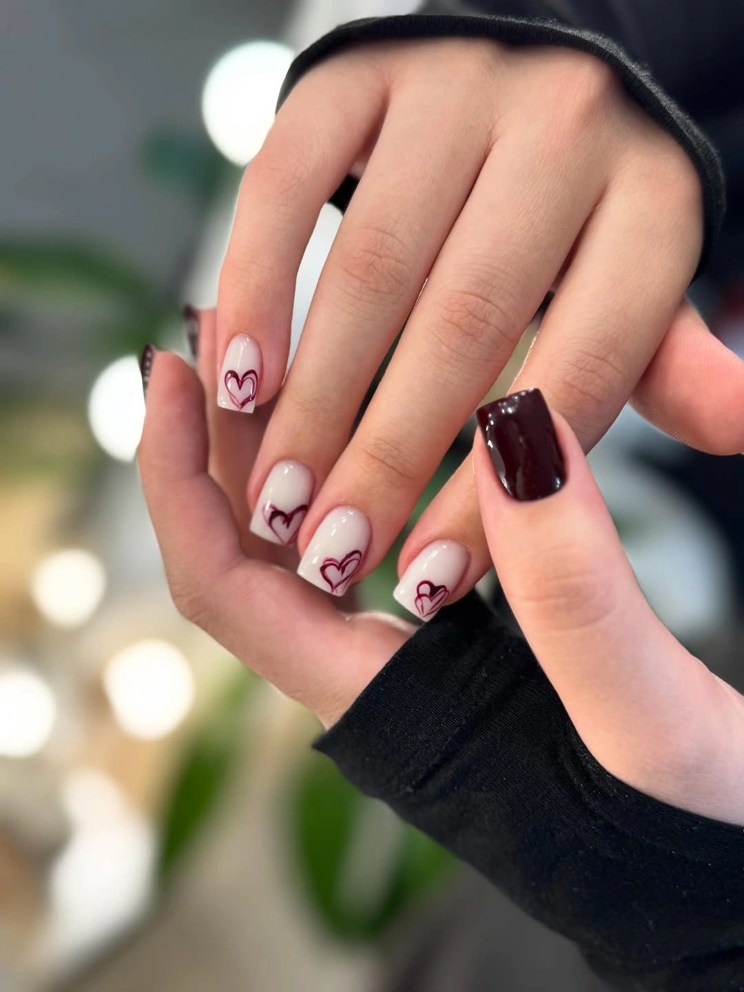 short nude nails with tiny red hearts and one wine accent