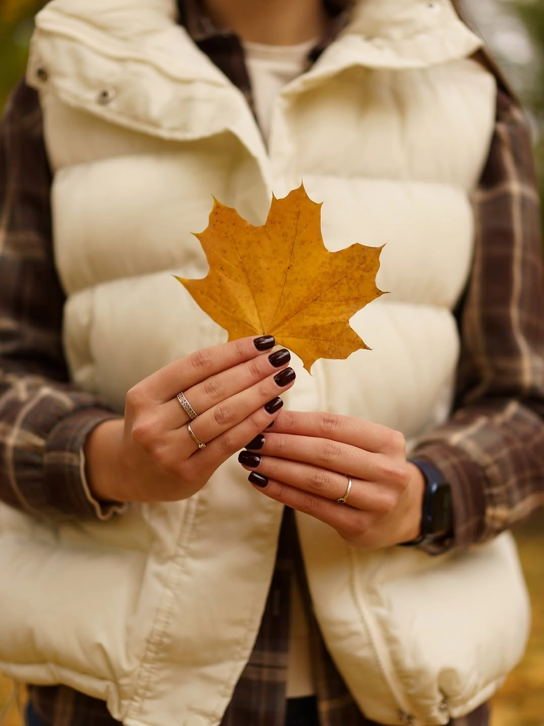 very short dark nails held beside a golden maple leaf