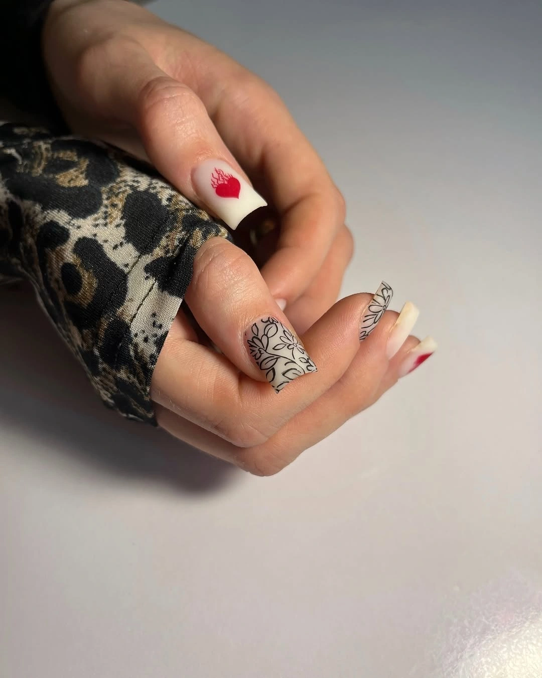 Square nails with black botanical lines and red hearts
