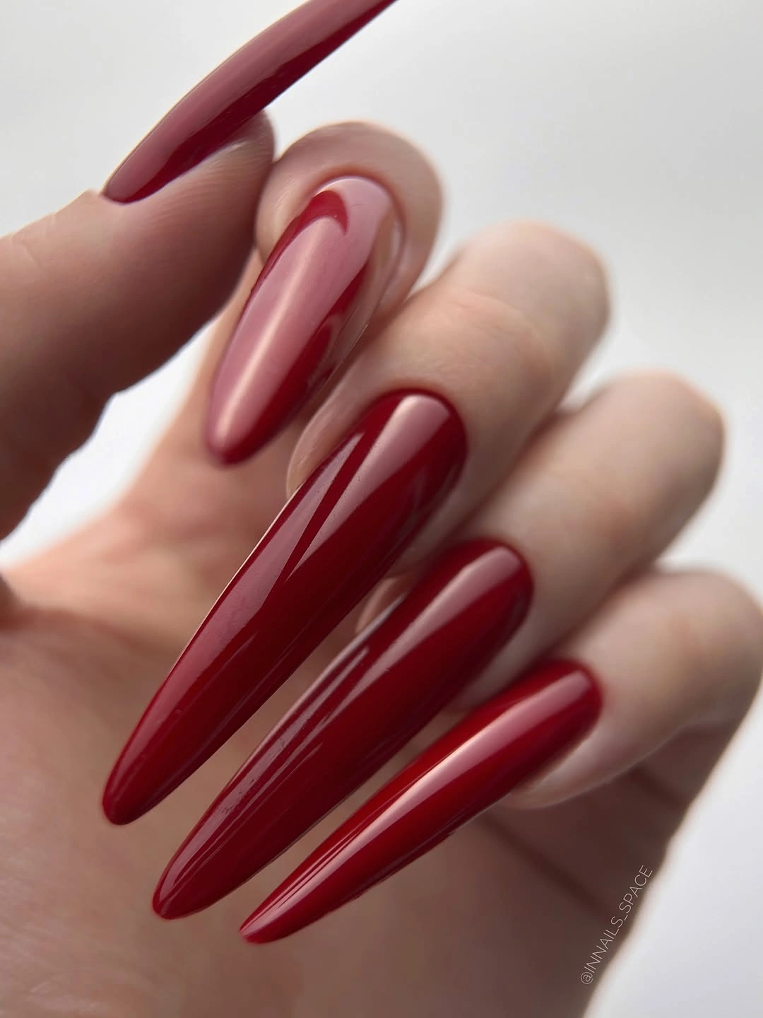 Glossy red stiletto nails with nude curved cutouts