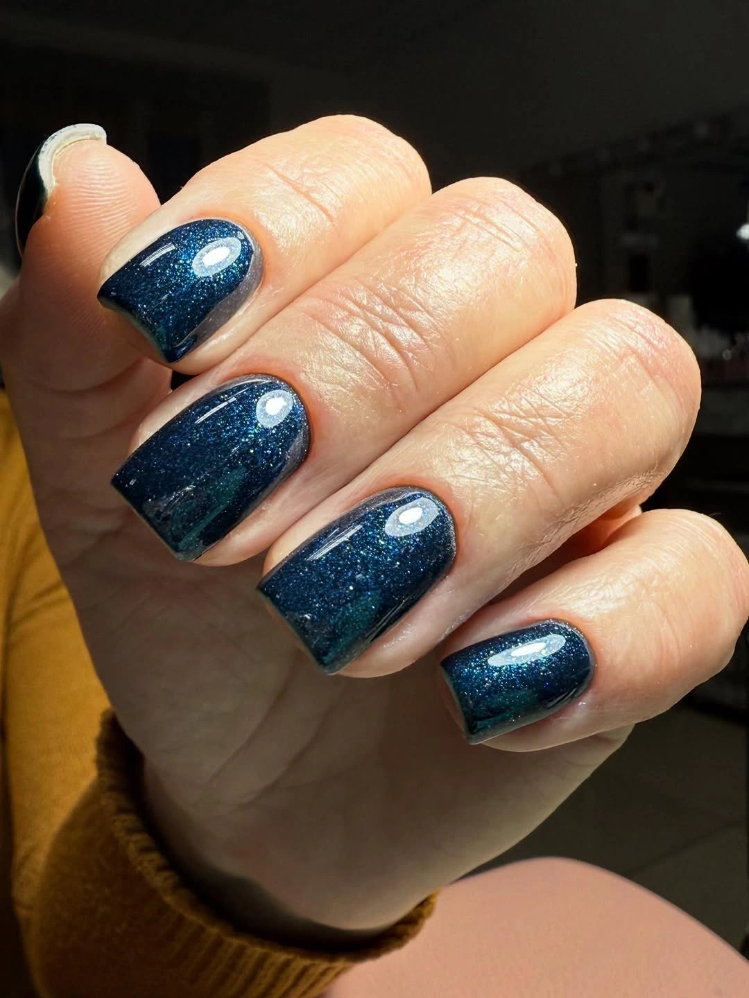 Short rounded nails with deep teal shimmer polish