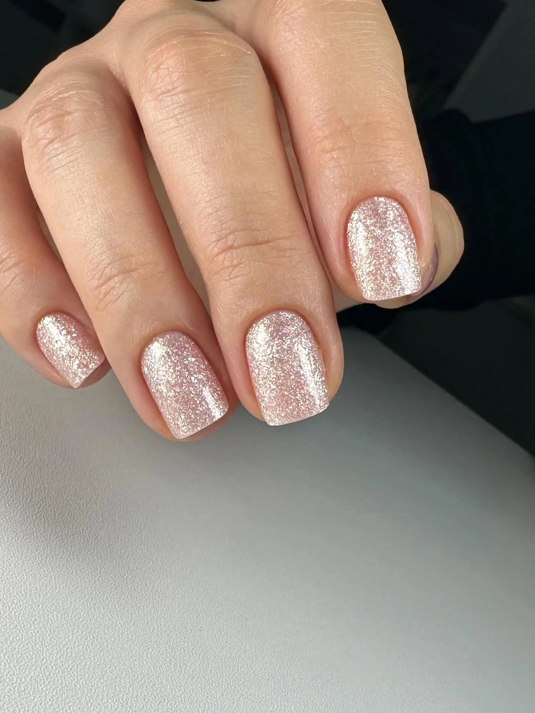 Short square nails covered in rose gold glitter