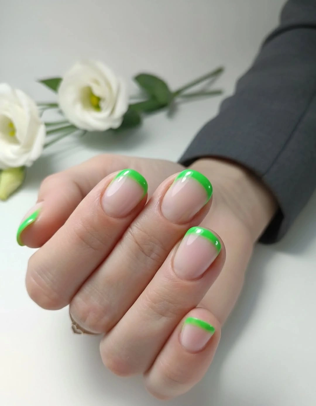 Nude rounded nails edged with neon green French lines