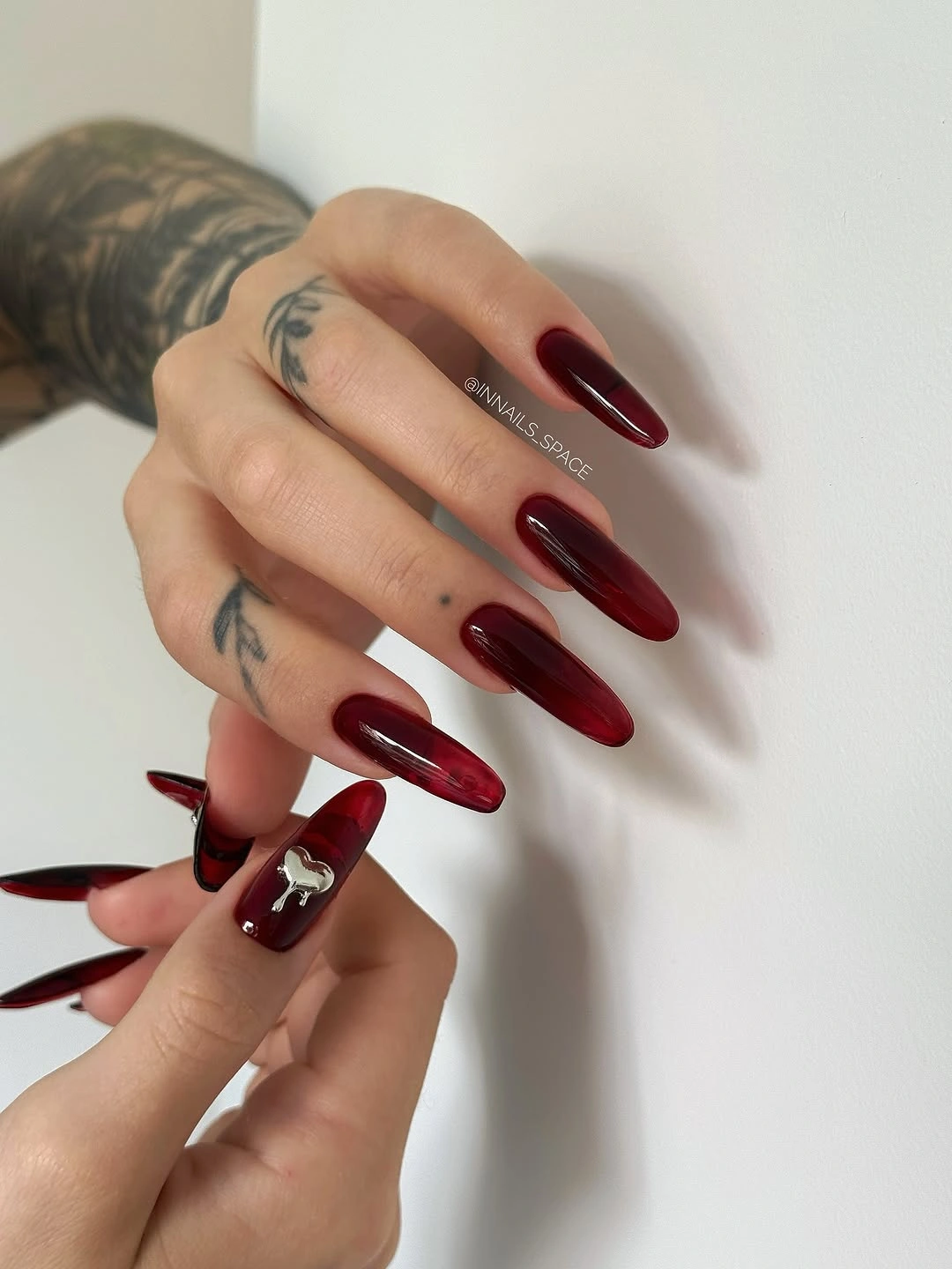 Long deep red stiletto nails with one sparkling accent