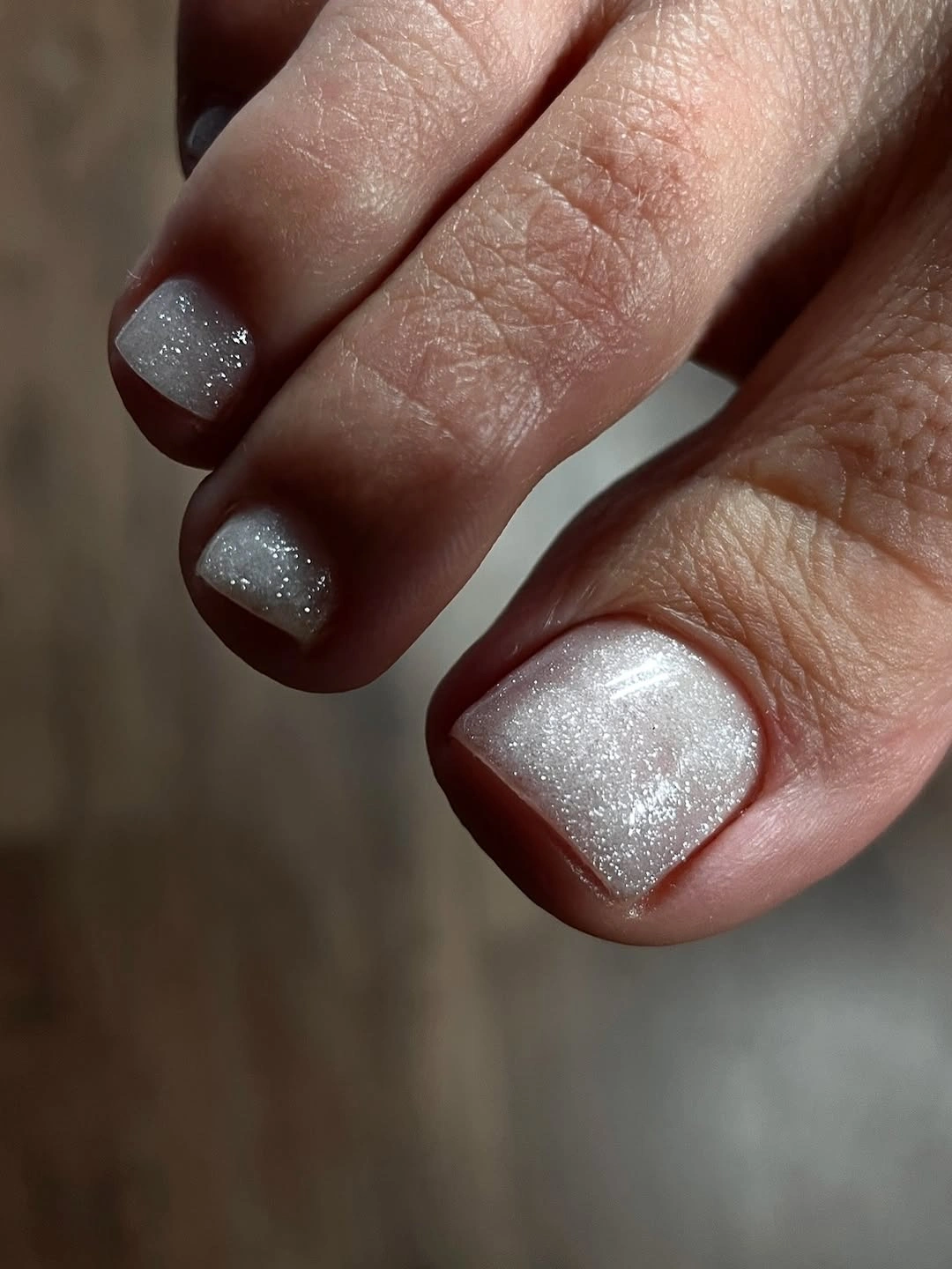 white glitter polish on short square toenails