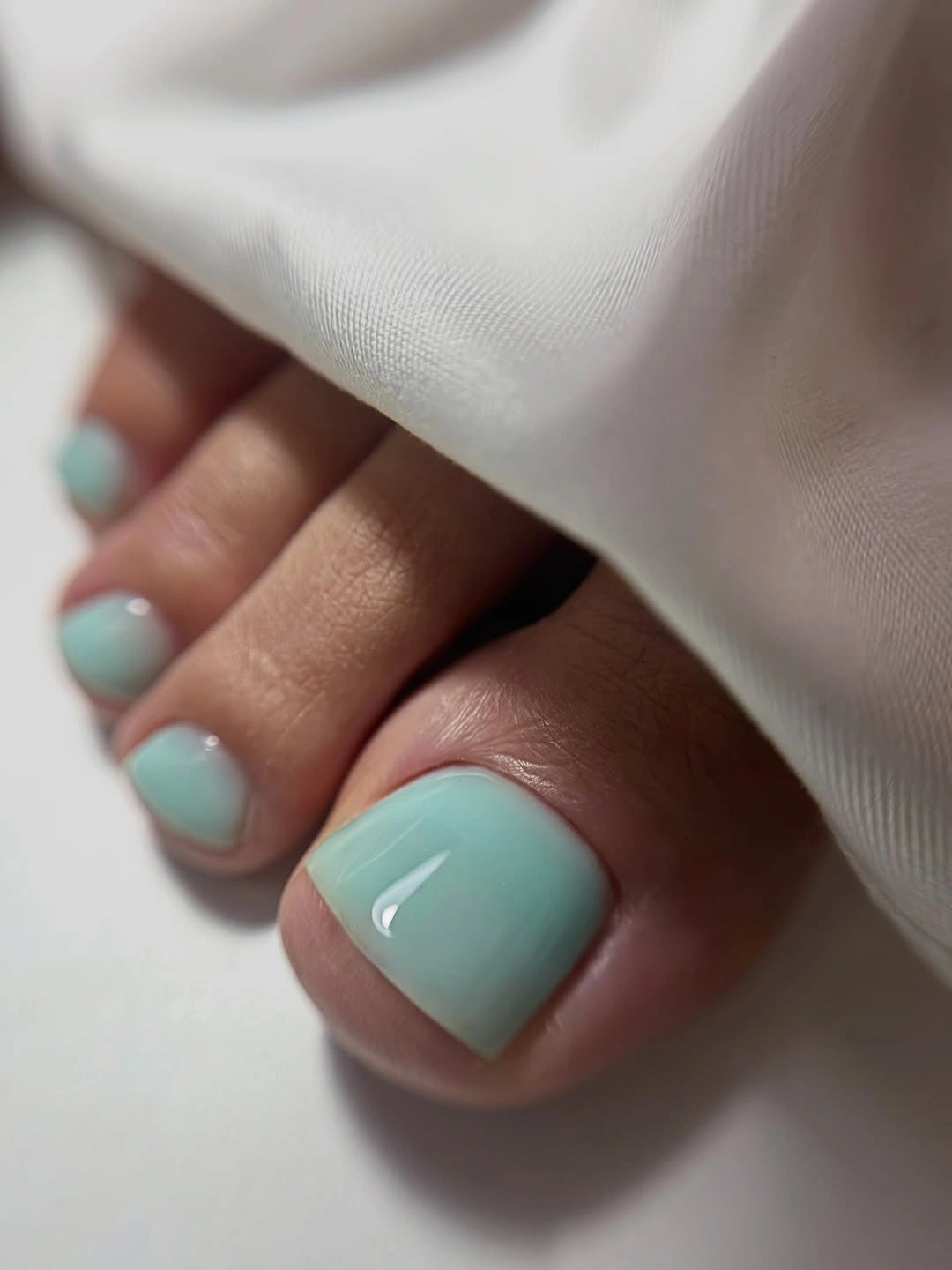pale mint glossy pedicure on short square toenails