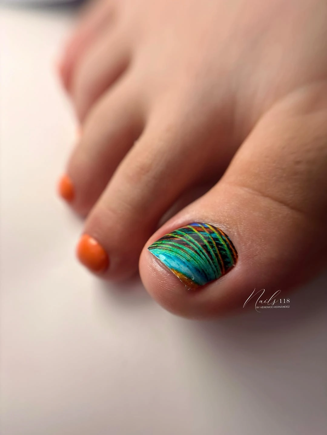 orange pedicure with painterly teal big toe accent