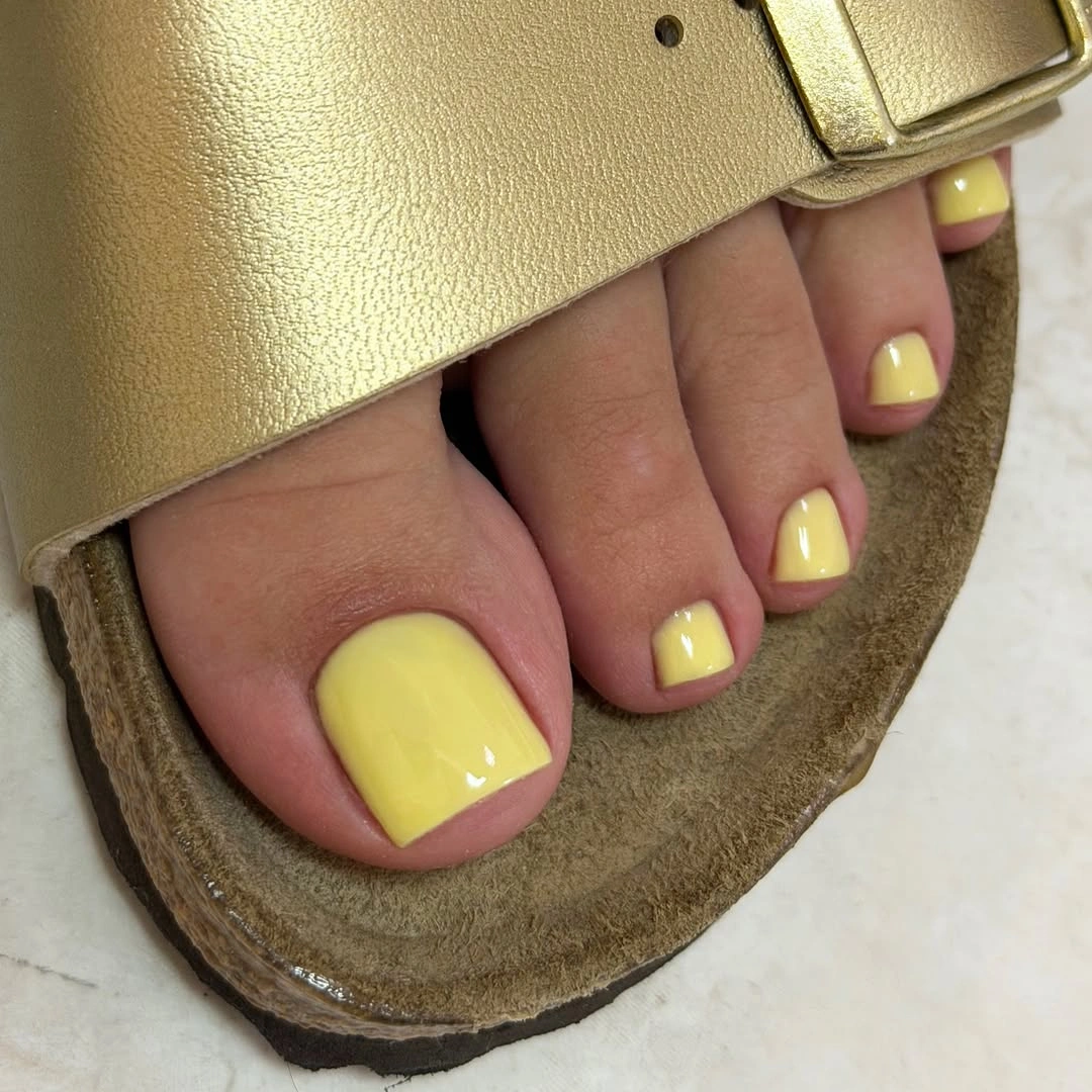 soft yellow pedicure framed by a gold sandal