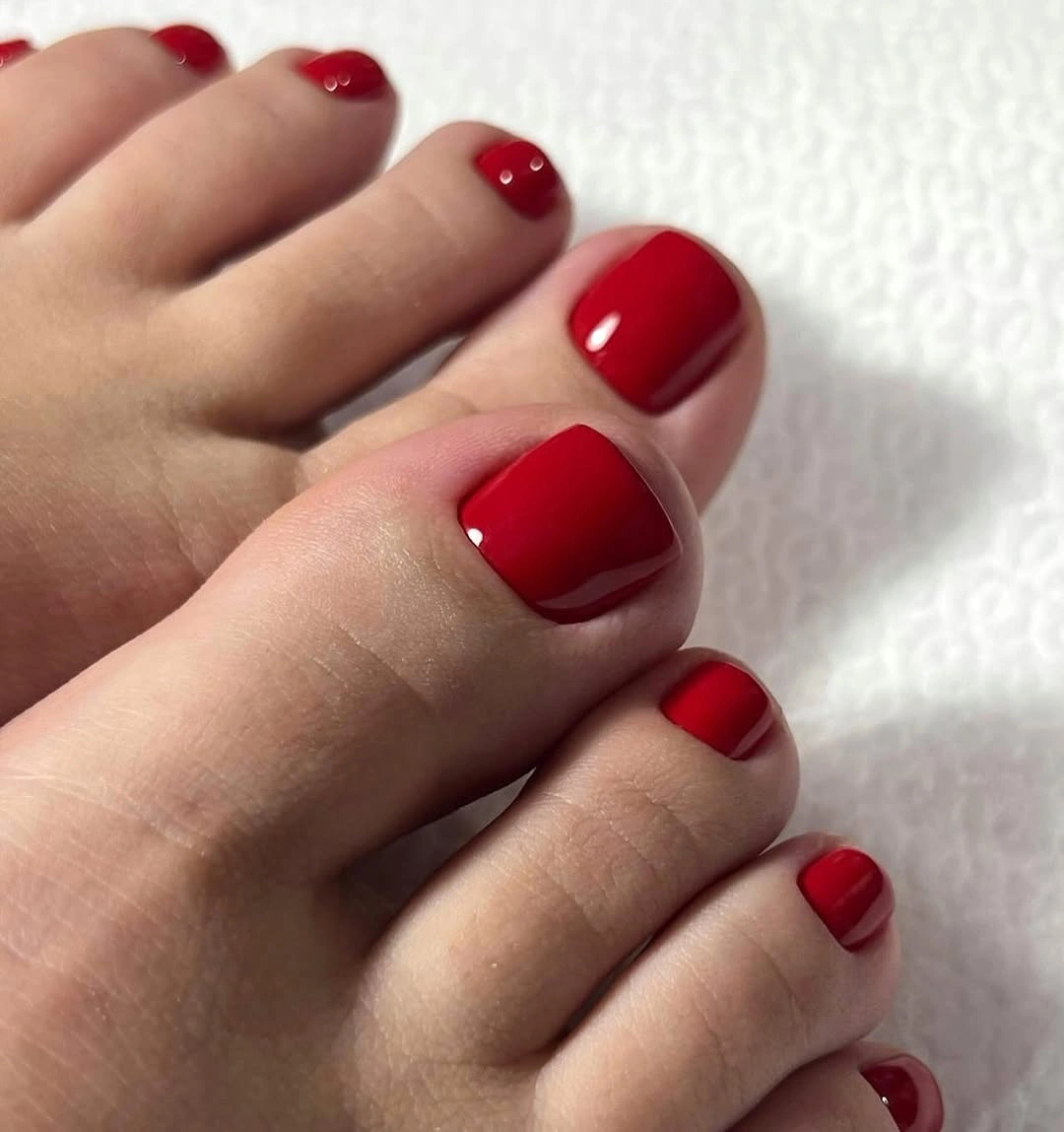 bright red glossy polish on short toenails