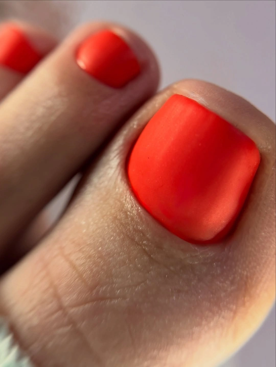 orange red satin looking polish on square toenails