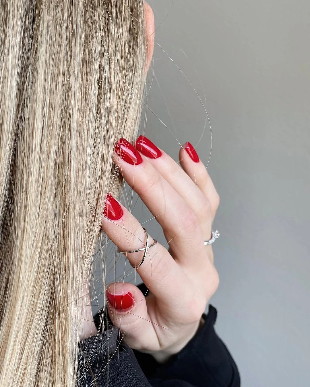Short glossy red nails with thin pale curved accents