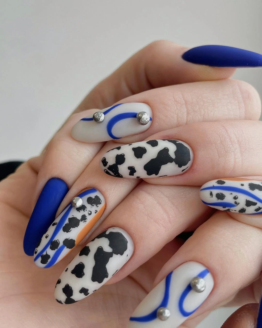 Blue almond nails with spotted white accents and curved lines