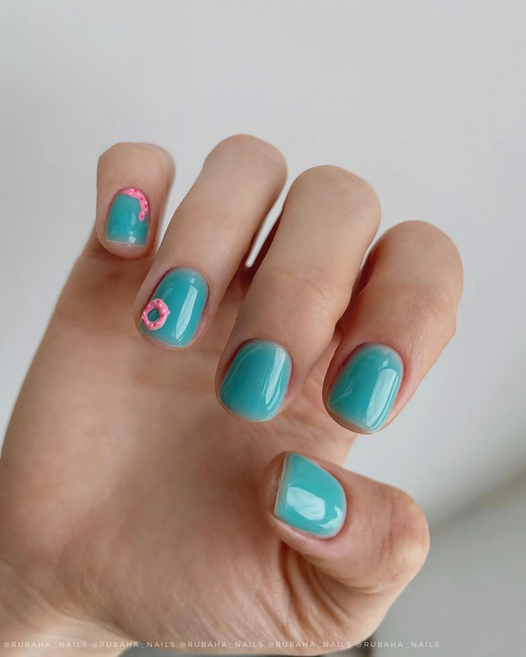 Short turquoise nails with small pink flower-like accents