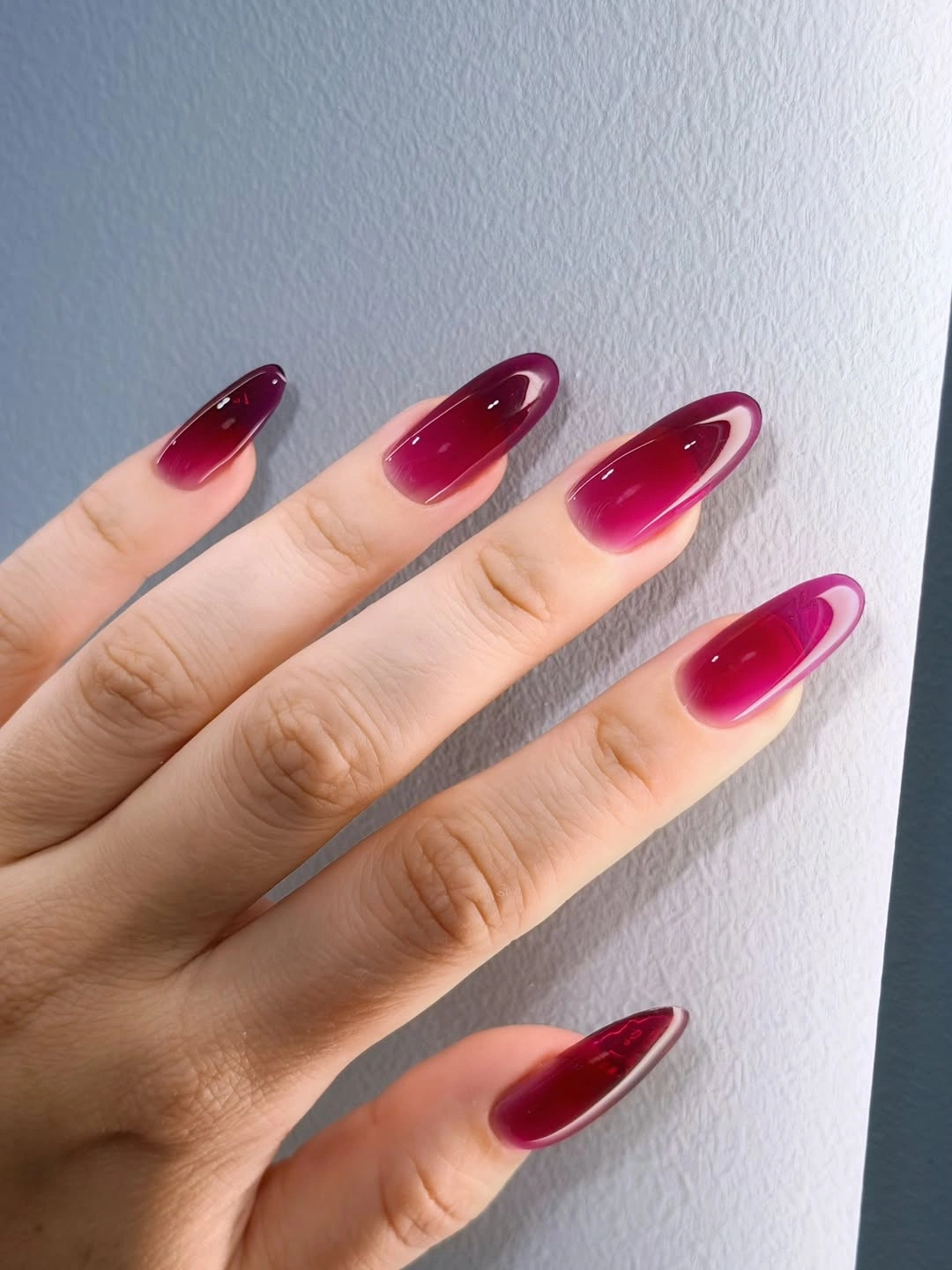Long glossy burgundy almond nails with a deeper tonal shift