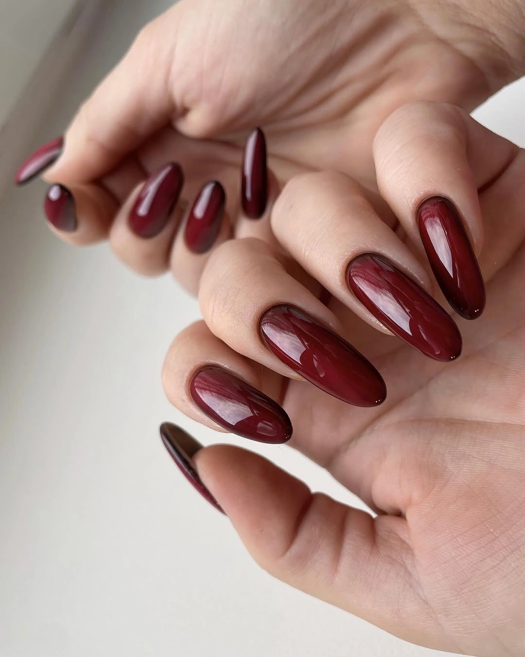 Long glossy burgundy red almond nails with a clean finish
