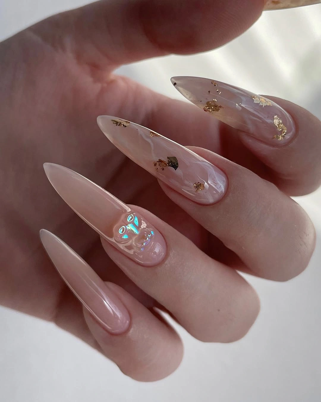 Long translucent pink pointed nails with gold flecks