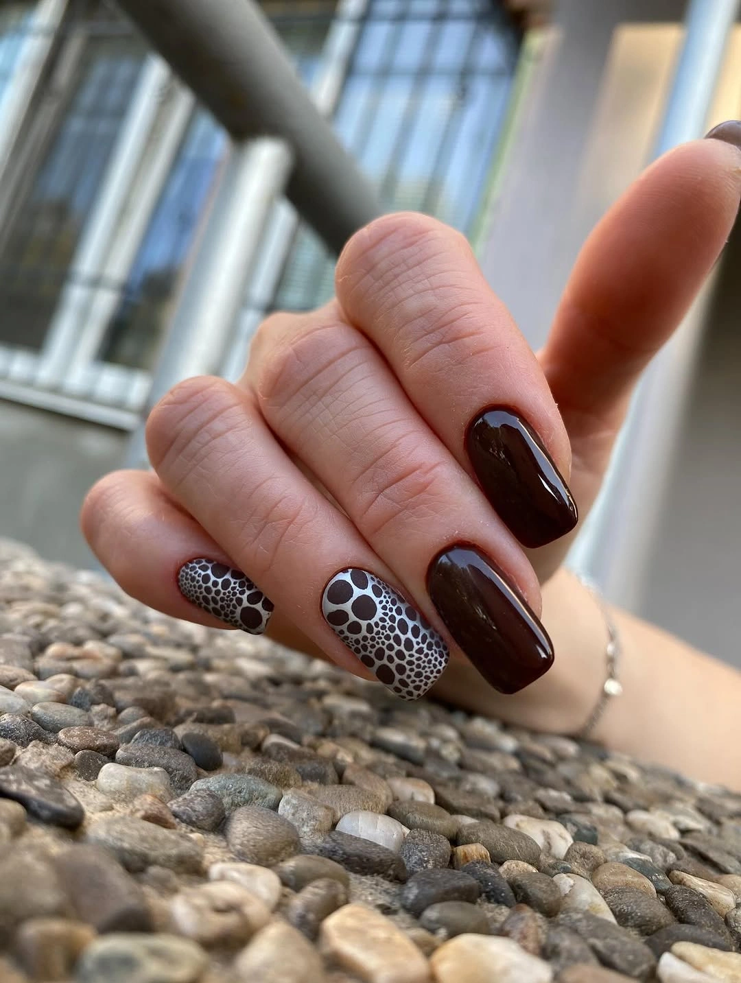 Chocolate almond nails with one black and brown dotted accent