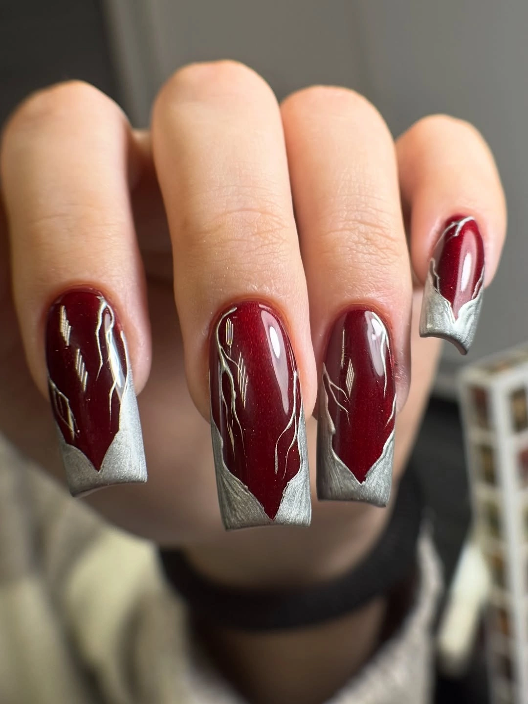 Long square burgundy nails with silver geometric tip accents