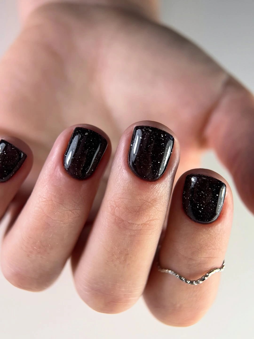 Short square black nails with scattered silver flecks
