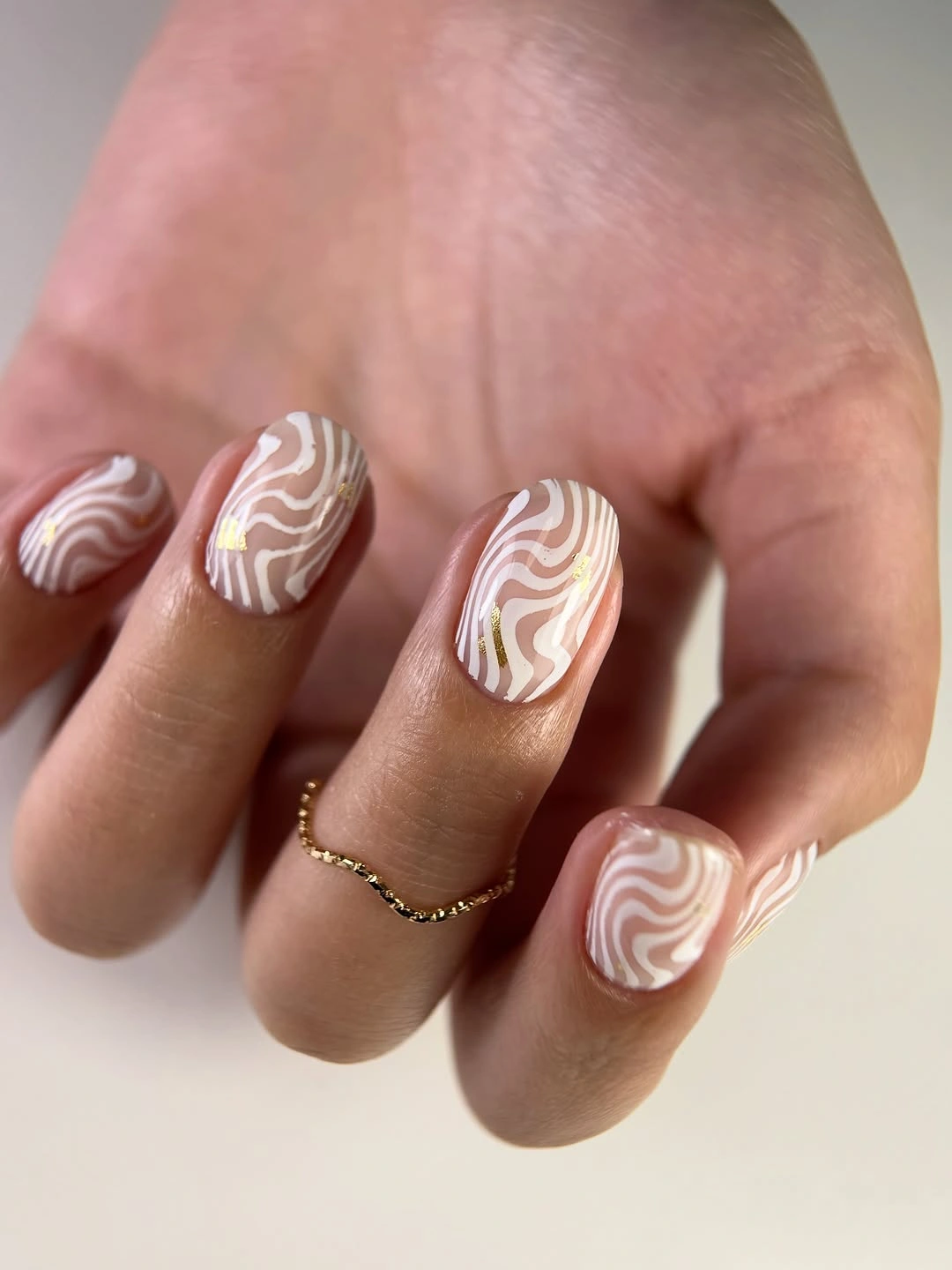 Short rounded nails with white waves and tiny gold accents
