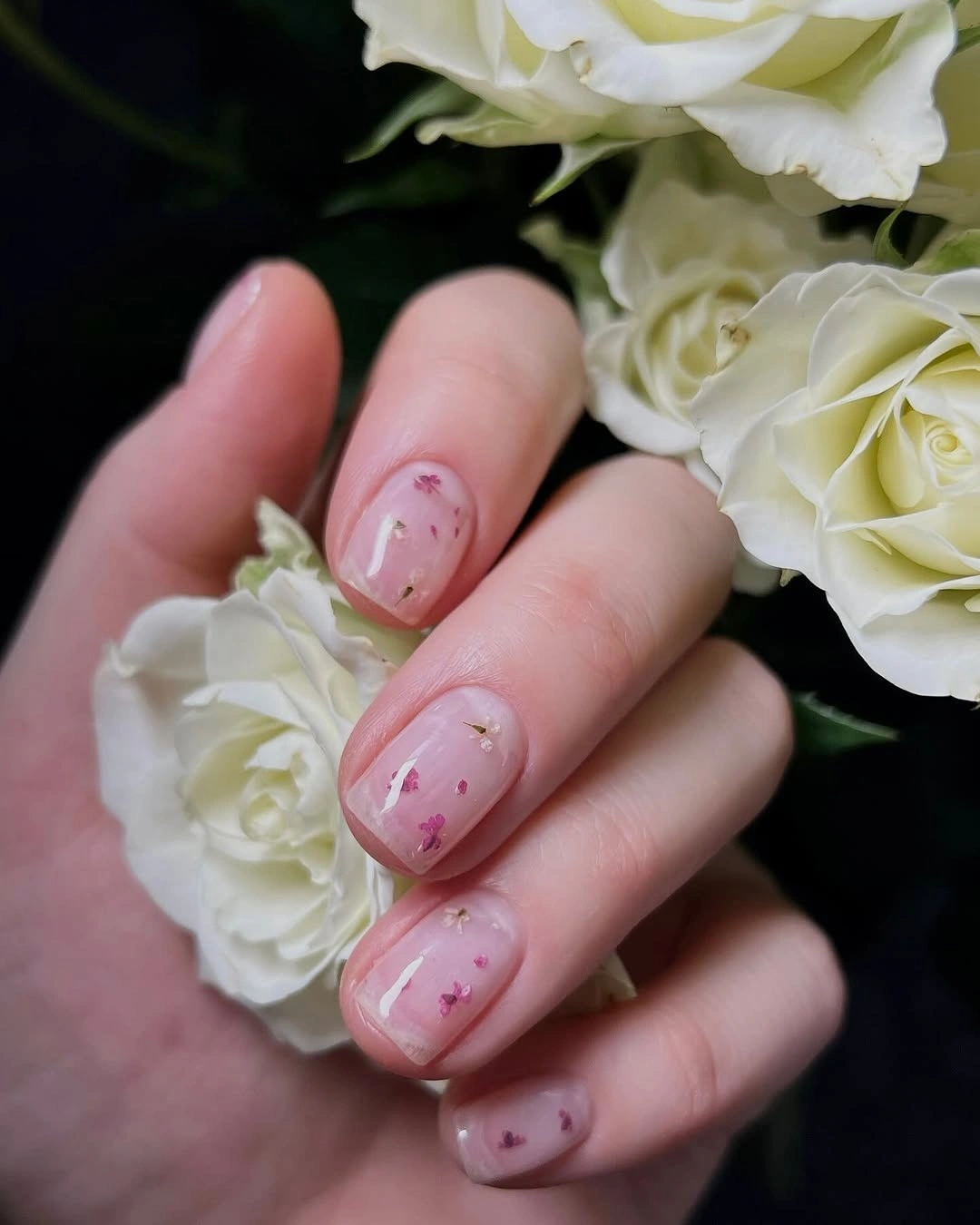 Short pale pink nails with tiny floral-like accents