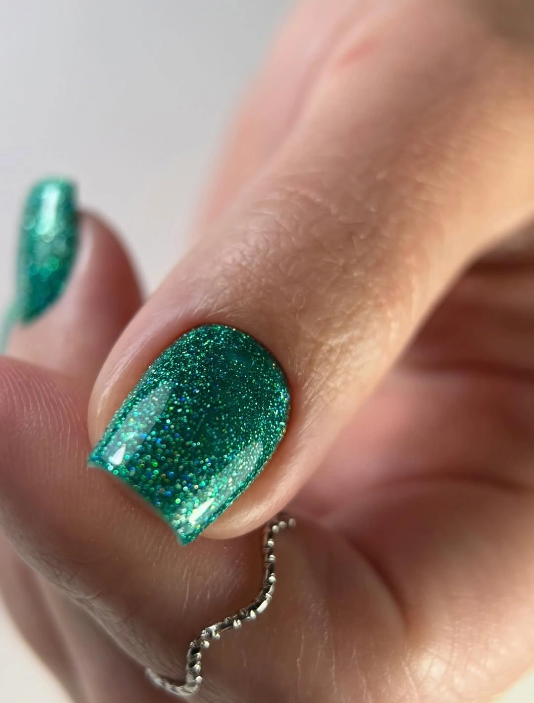 Short square emerald green nails covered in fine glitter