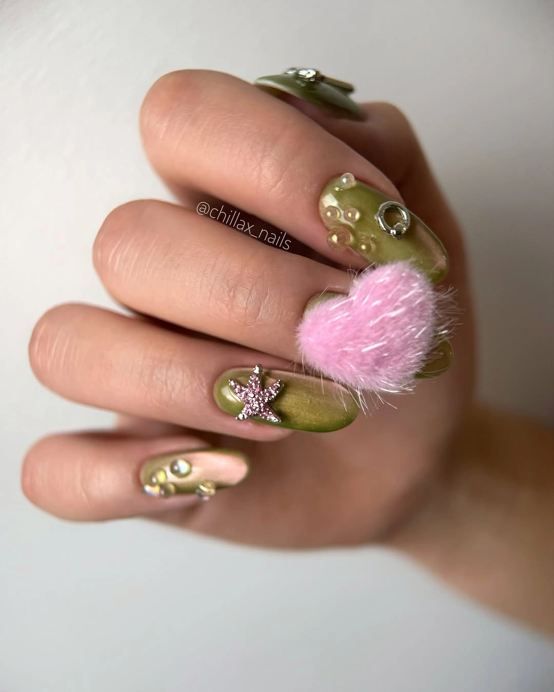 Medium oval olive nails with tiny accents and one fluffy pink detail