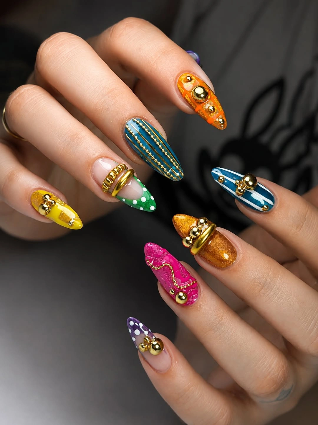 Long stiletto nails in jewel colors with warm decorative accents