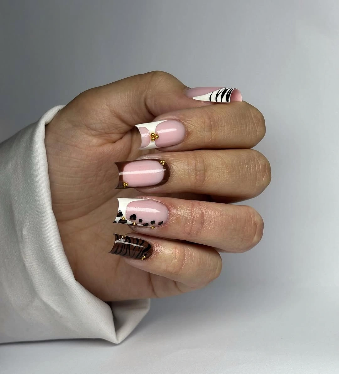 Medium square pale pink nails with one dark spotted accent