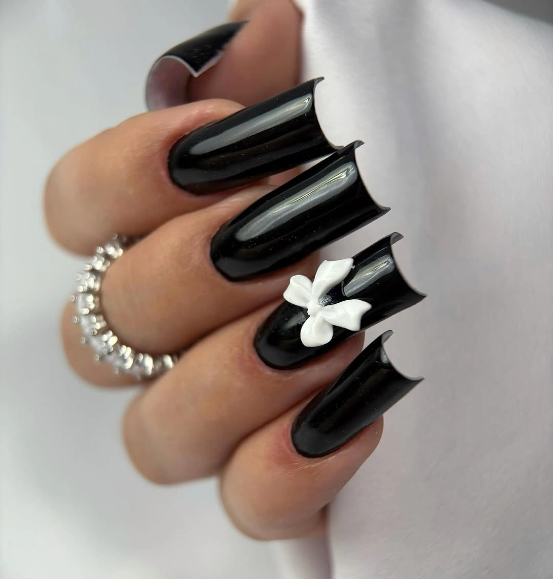 Very long glossy black square nails with one white bow accent