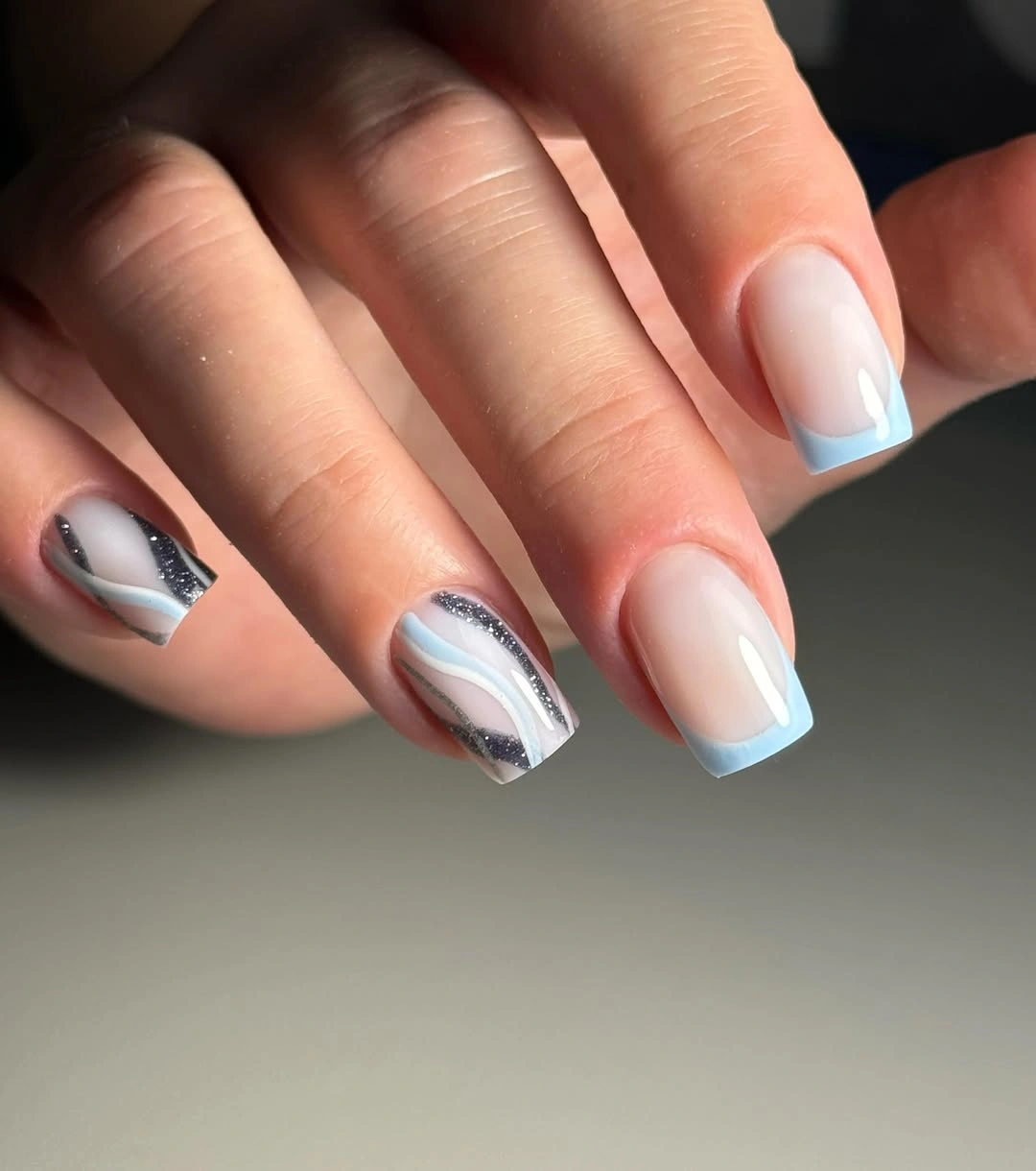 Pale blue French tip nails with wavy accents