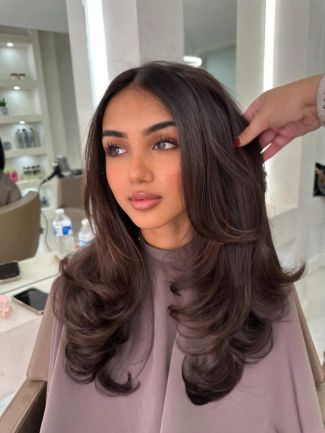 Medium brown layered blowout with feathered framing and plum-red tone