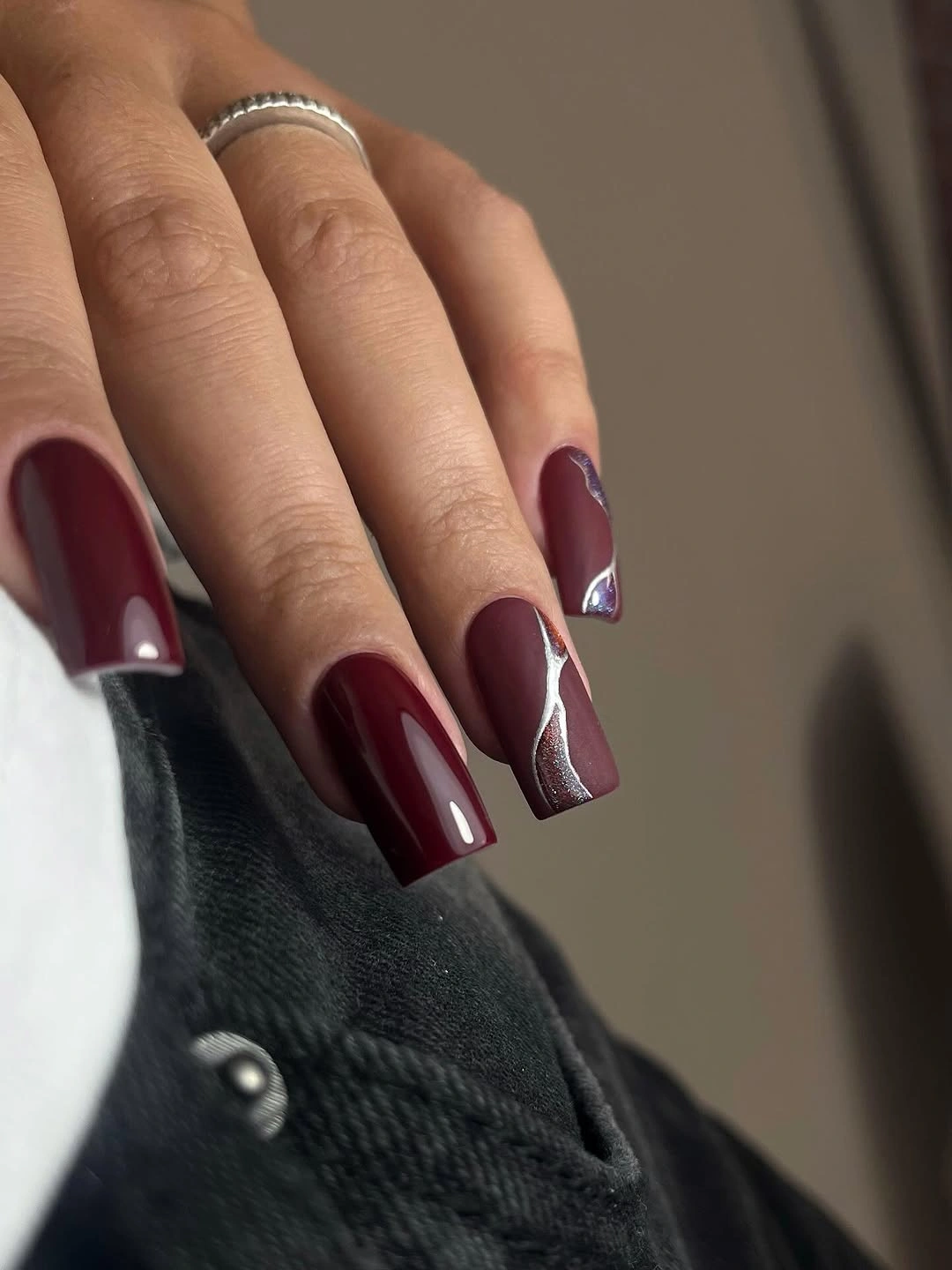 Long burgundy square nails with a narrow silver accent stripe