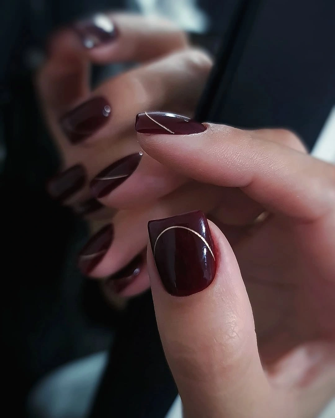 Burgundy nails with a pale diagonal negative-space accent