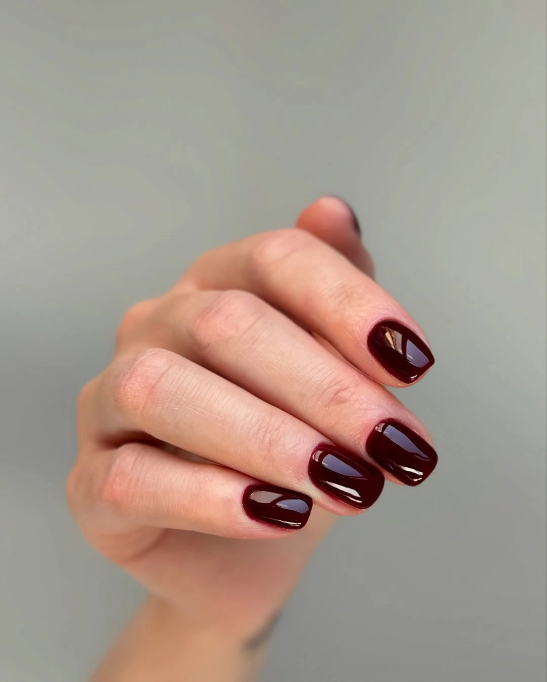Medium rounded-square burgundy nails with glossy depth
