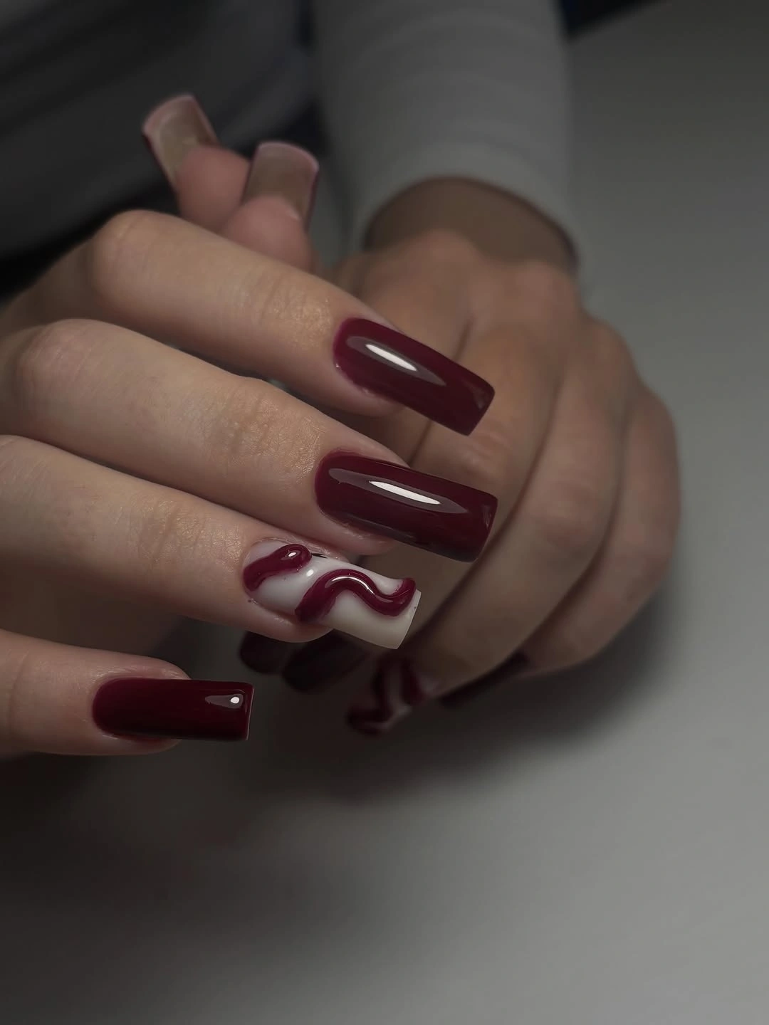 Long square burgundy nails with cream wavy accent lines