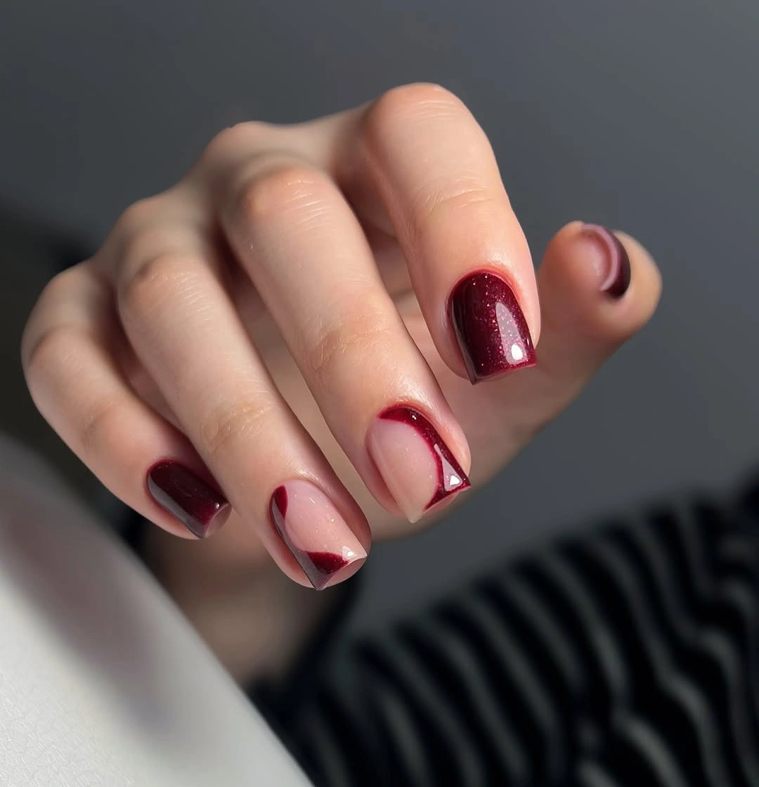 Short burgundy rounded-square nails with tiny pale accents