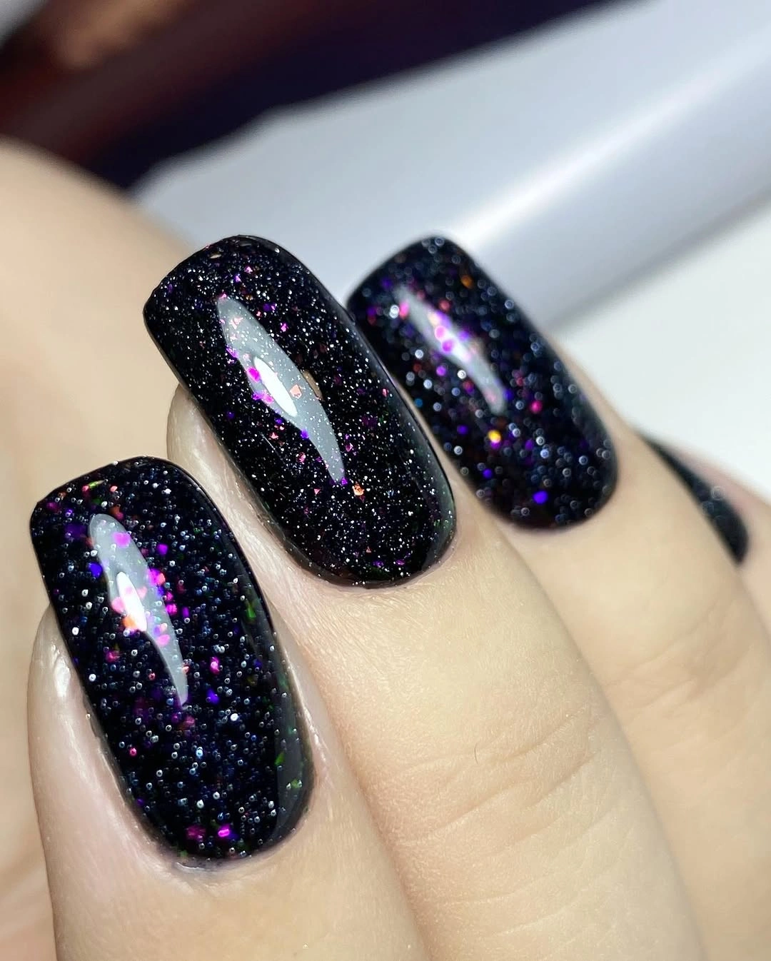 Rounded dark nails with blue violet and silver multicolor sparkle