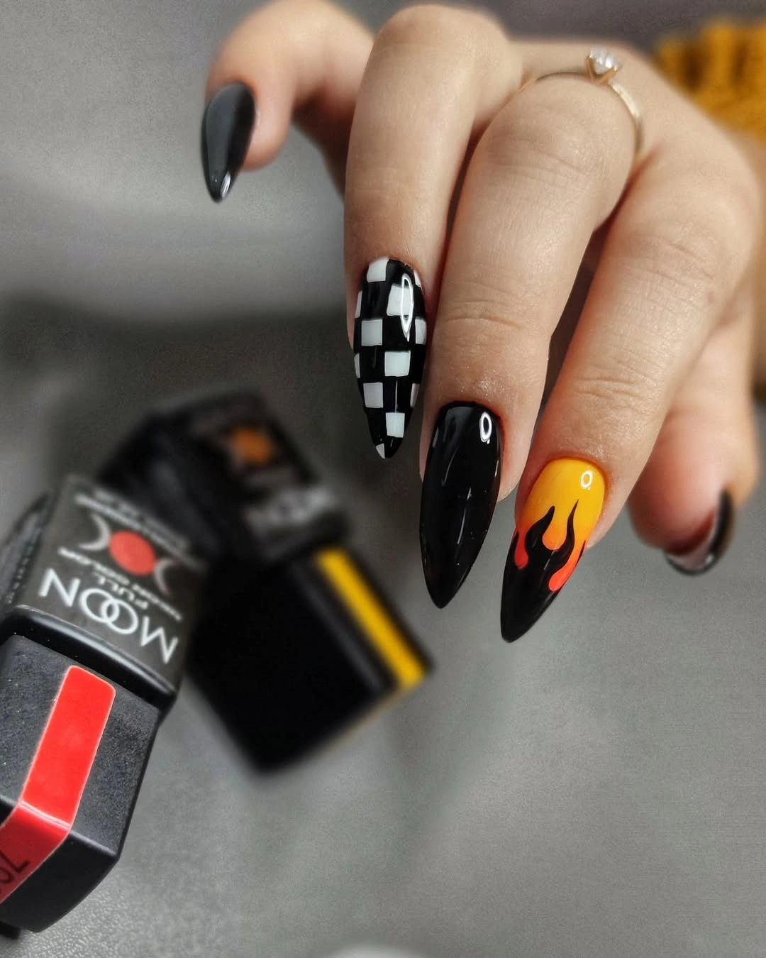 Long black almond nails with checker and warm orange accent details