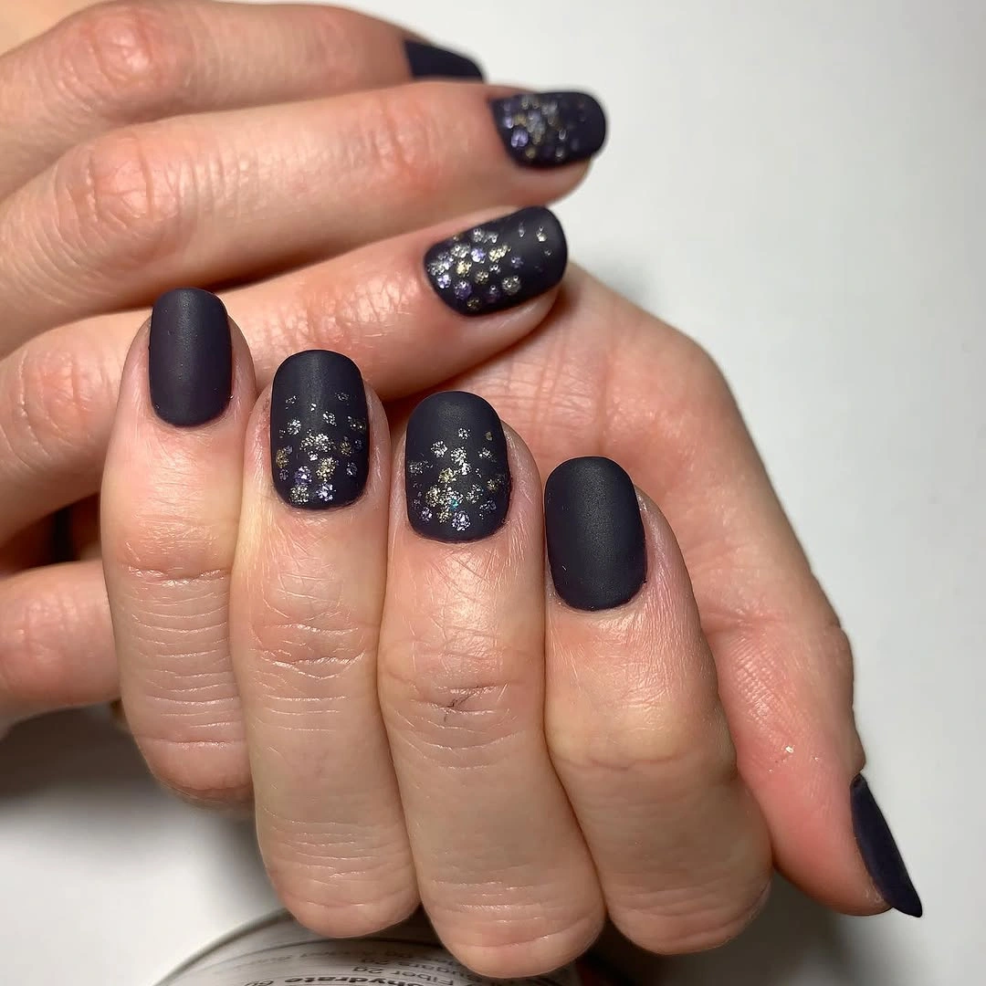 Matte dark almond nails with scattered tiny silver accents